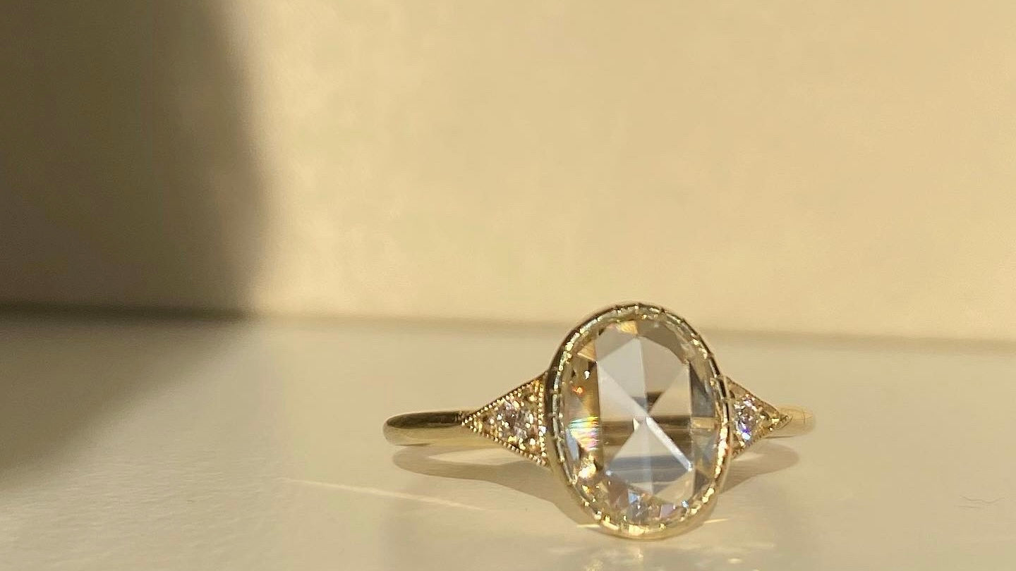 14k yellow gold custom engagement ring with oval white diamond center stone and white side diamonds