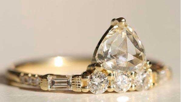 14k yellow gold custom engagement ring with pear cut white diamond center stone, baguette and pave white diamonds