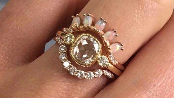 14k yellow gold custom ring with square white diamond center stone and two white diamonds and milgrain stacked with two arched 14k yellow gold rings with opals and white diamond arched band
