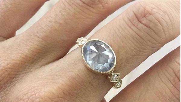 14k yellow gold custom ring with rustic diamond center stone and milgrain and white diamond side stones on hand