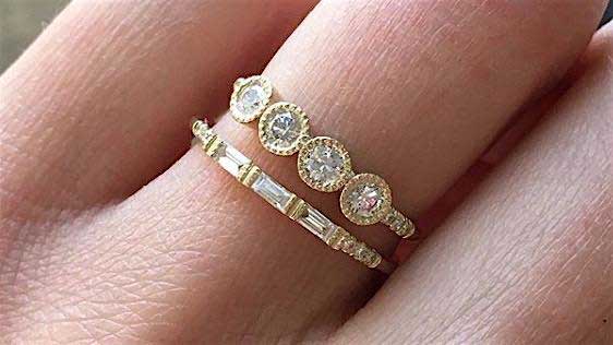 14k yellow gold custom ring with four round white diamonds with milgrain detail and pave white diamonds stacked with white diamond baguette band on hand 