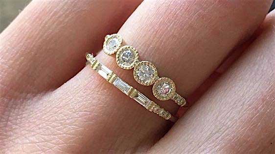 14k yellow gold custom ring with four round white diamonds with milgrain detail and pave white diamonds stacked with white diamond baguette band on hand