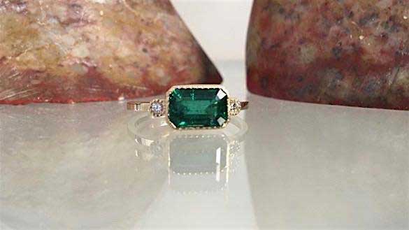 14k yellow gold custom ring with princess cut emerald center stone with milgrain detail and white diamond side stones (Lexie Style)
