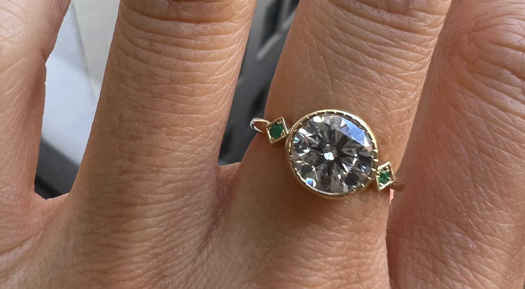 14k yellow gold custom engagement ring with round white diamond center stone and deco emerald squares