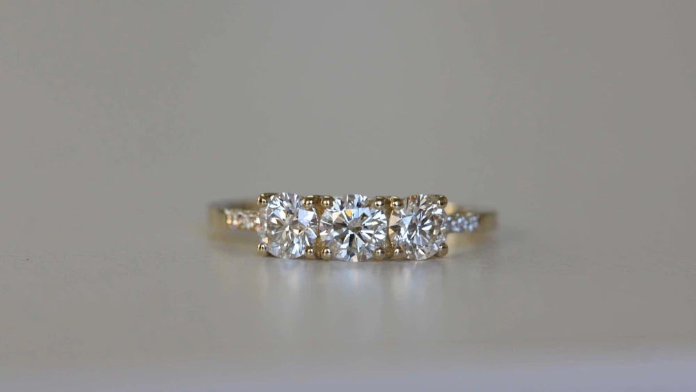 14k yellow gold custom engagement ring with three round cut white diamond center stones and pave white diamonds