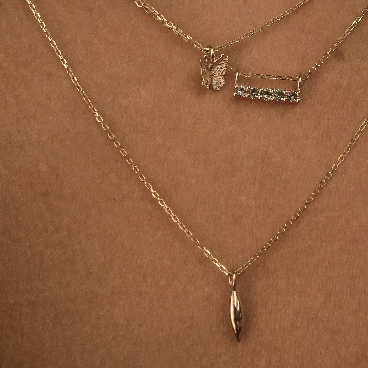 Three gold necklaces on a brown background