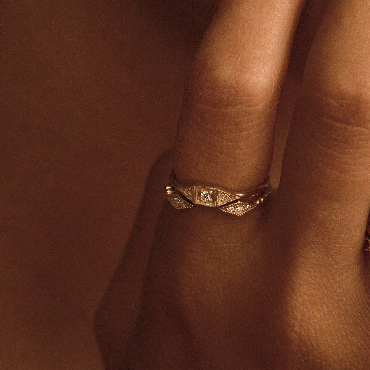 Gold ring on a finger with a warm brown background