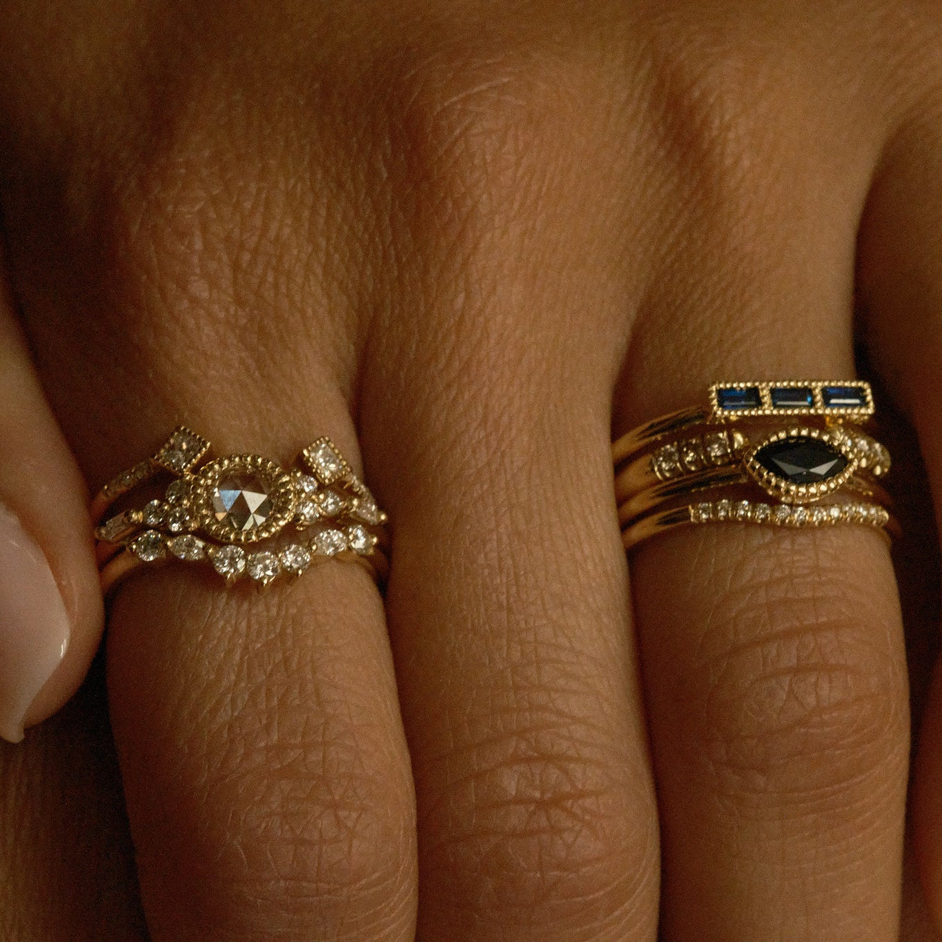 Close-up of a hand wearing two gold rings with gemstones.