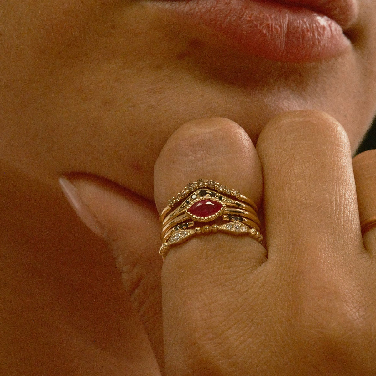 Close-up of a hand wearing a gold ring with a red gemstone.