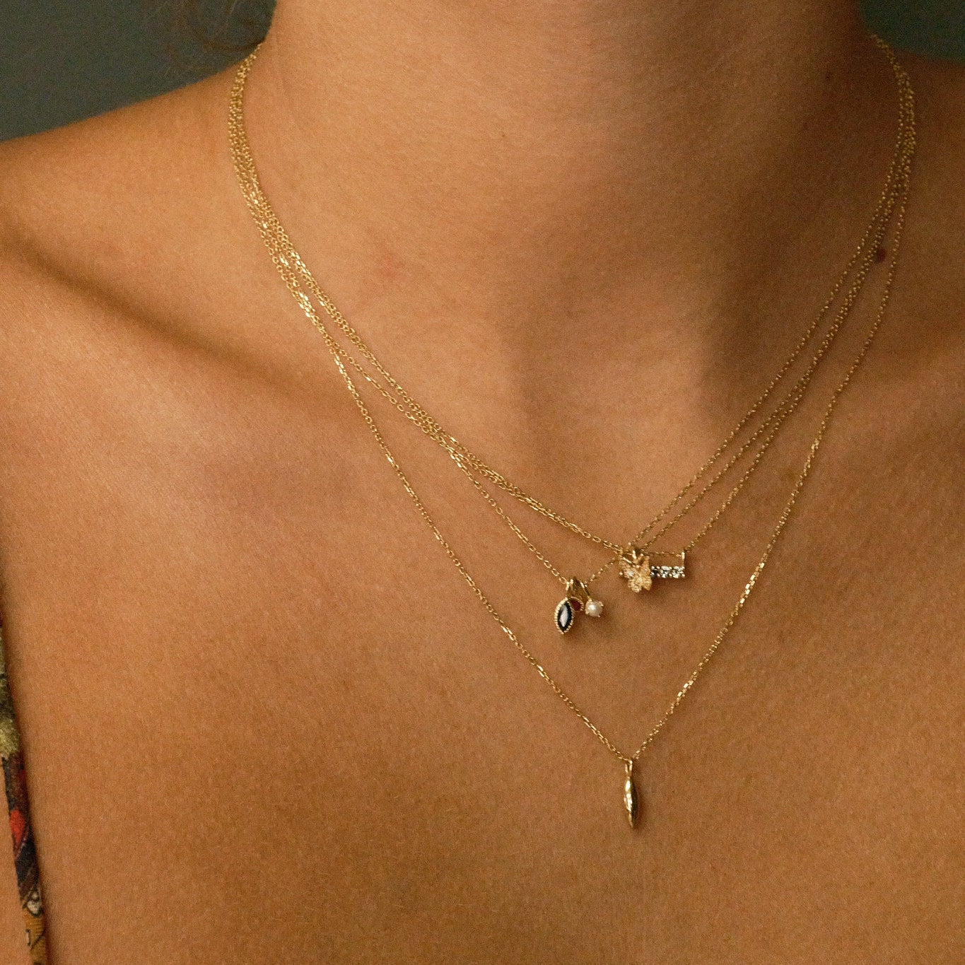 Close-up of a person wearing gold necklaces with small pendants.