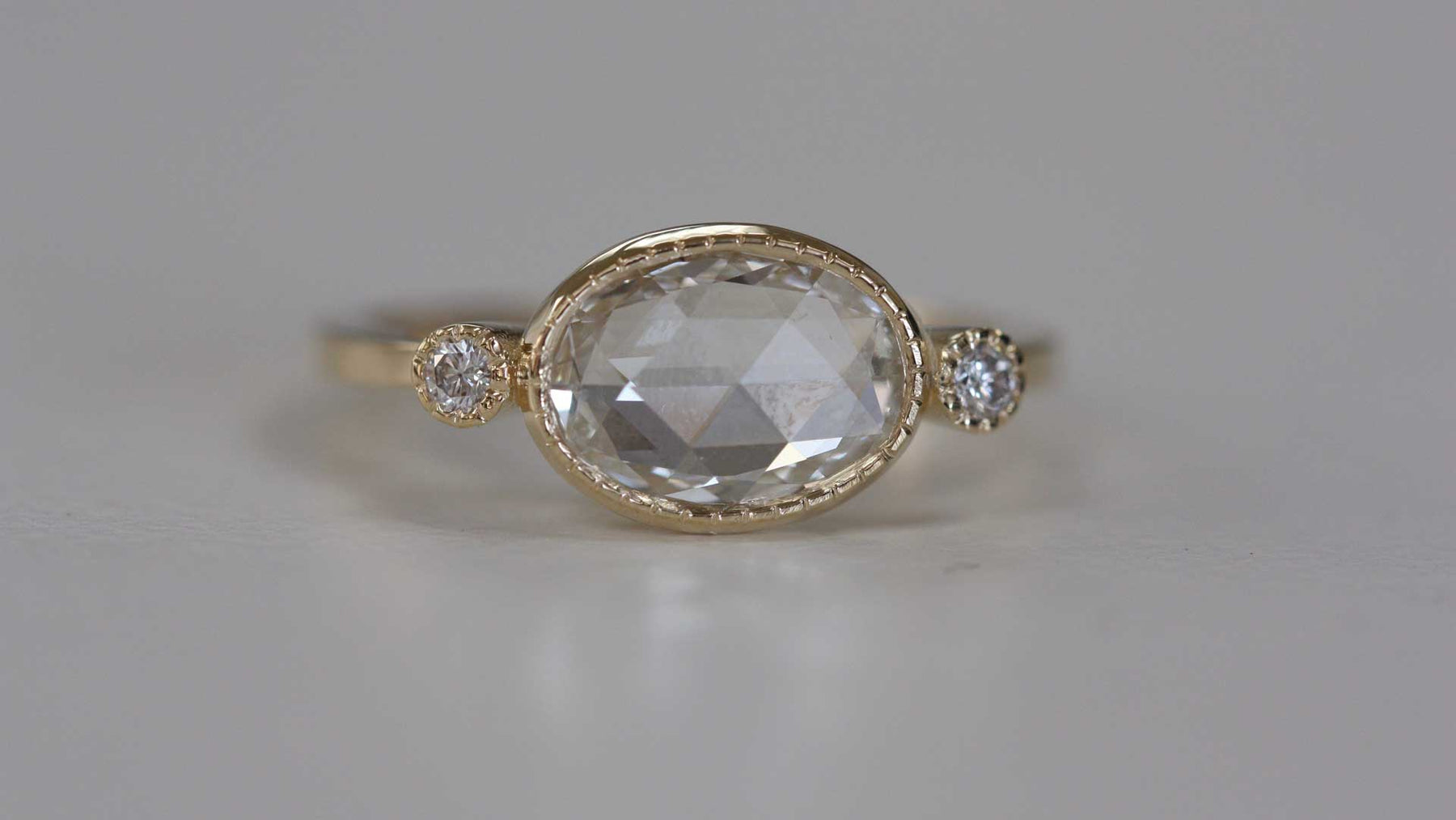 14k yellow gold custom engagement ring with two white side diamonds and milgrain detail