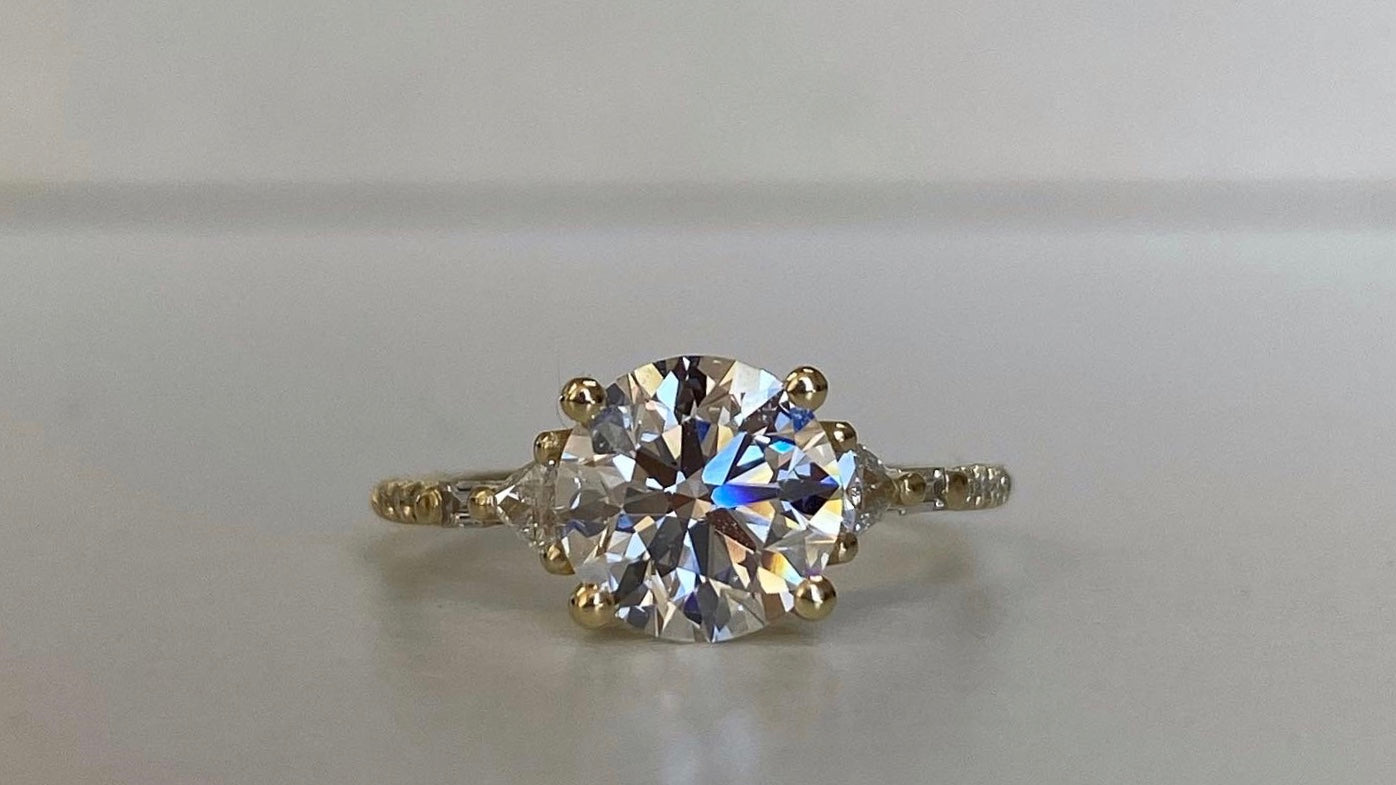 14k yellow gold custom ring with brilliant cut white diamond center stone and white diamond pave equilibrium style stones