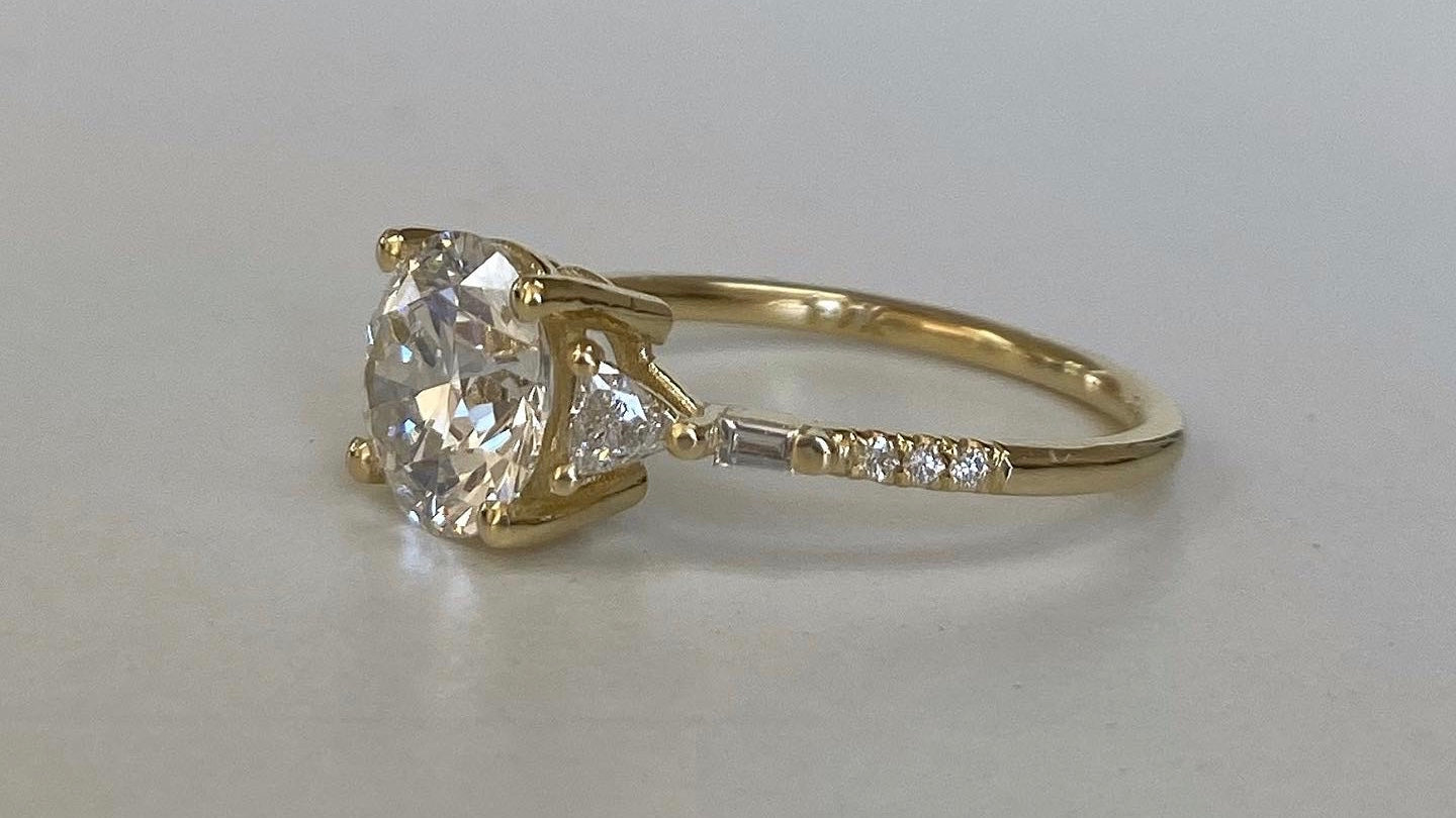 14k yellow gold custom ring with brilliant cut white diamond center stone and white diamond equilibrium side diamonds