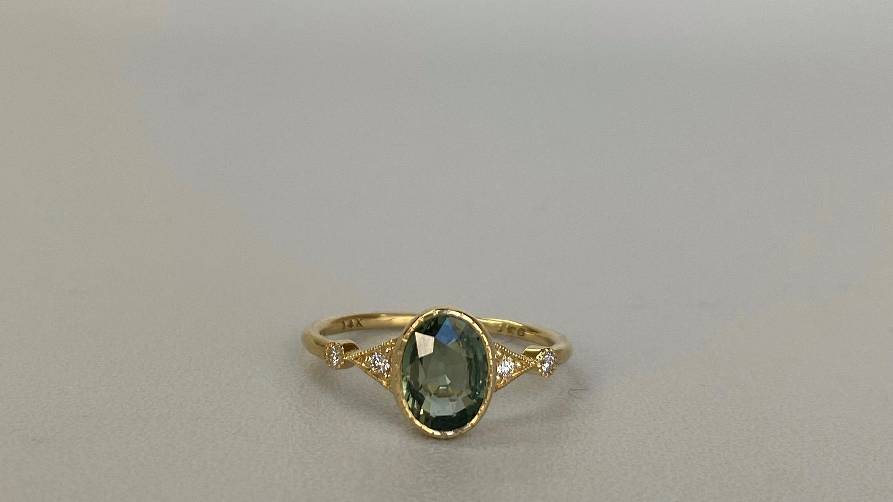 14k yellow gold custom ring with blue sapphire oval cut center stone with white diamond side stones