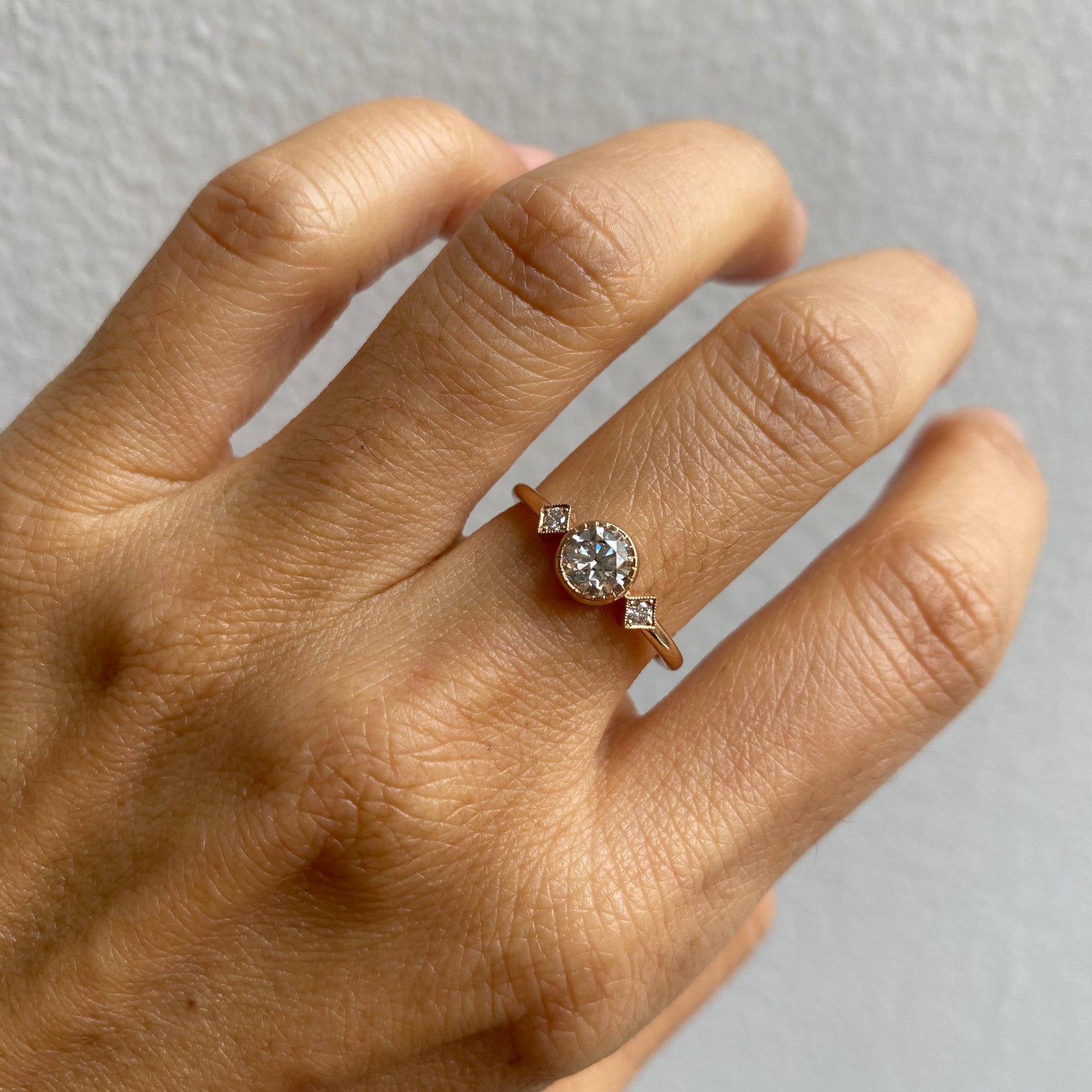 14k yellow gold custom ring with white diamond center stone and white diamond side stones on hand