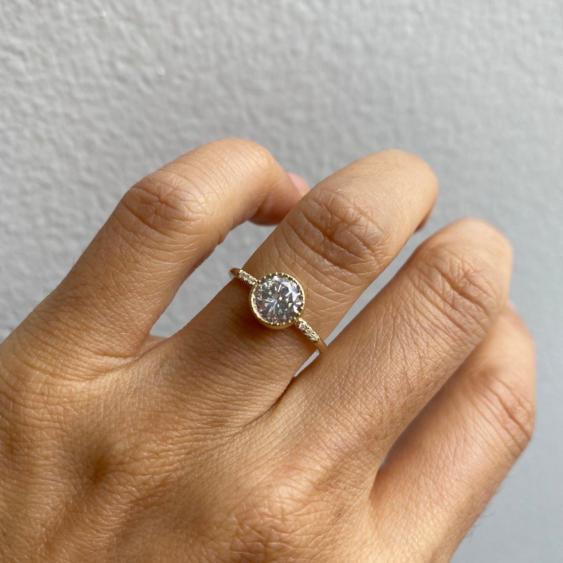 14k yellow gold custom ring with white diamond round cut center stone and milgrain detail on hand