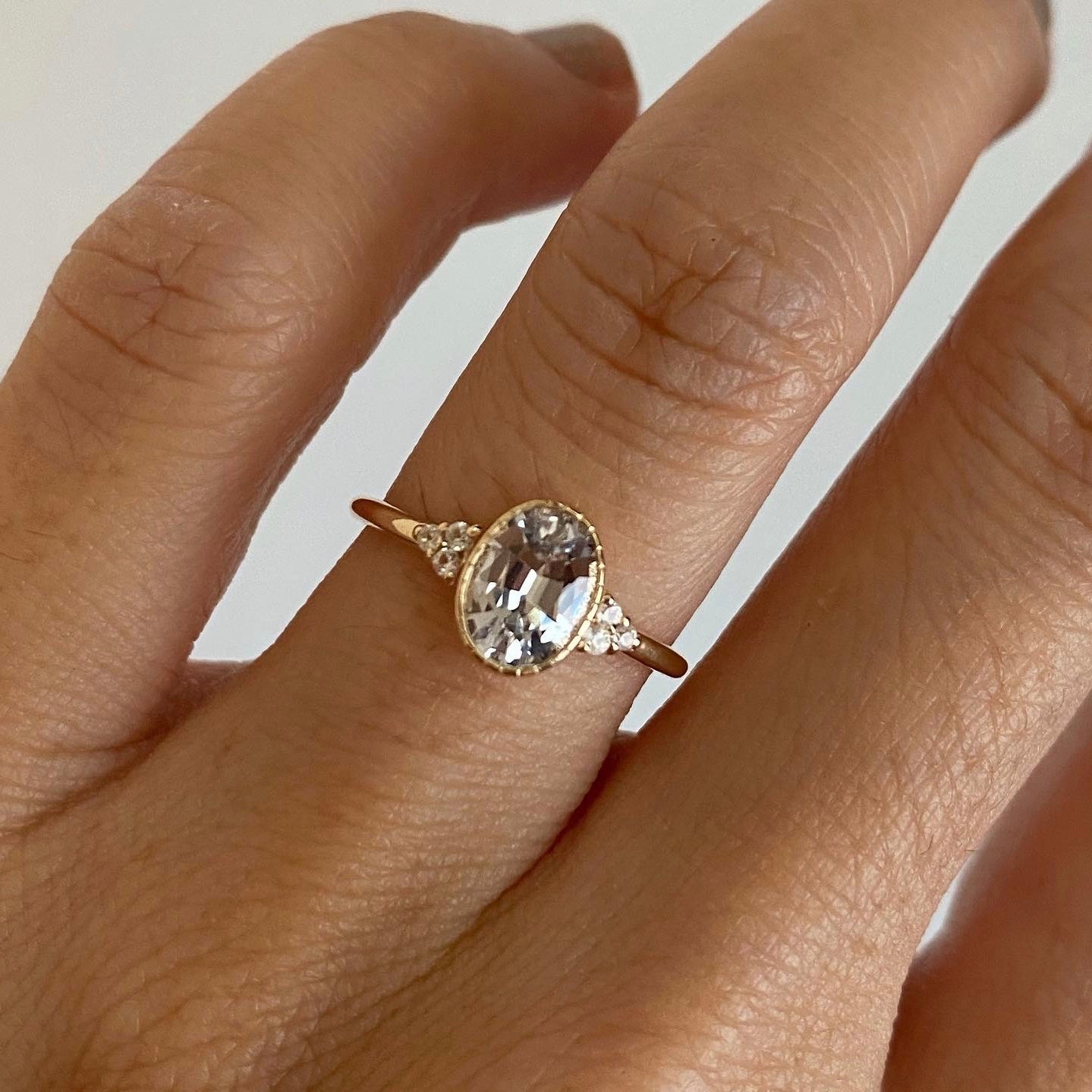 14k yellow gold custom ring with oval cut white diamond center stone and white side diamonds on hand
