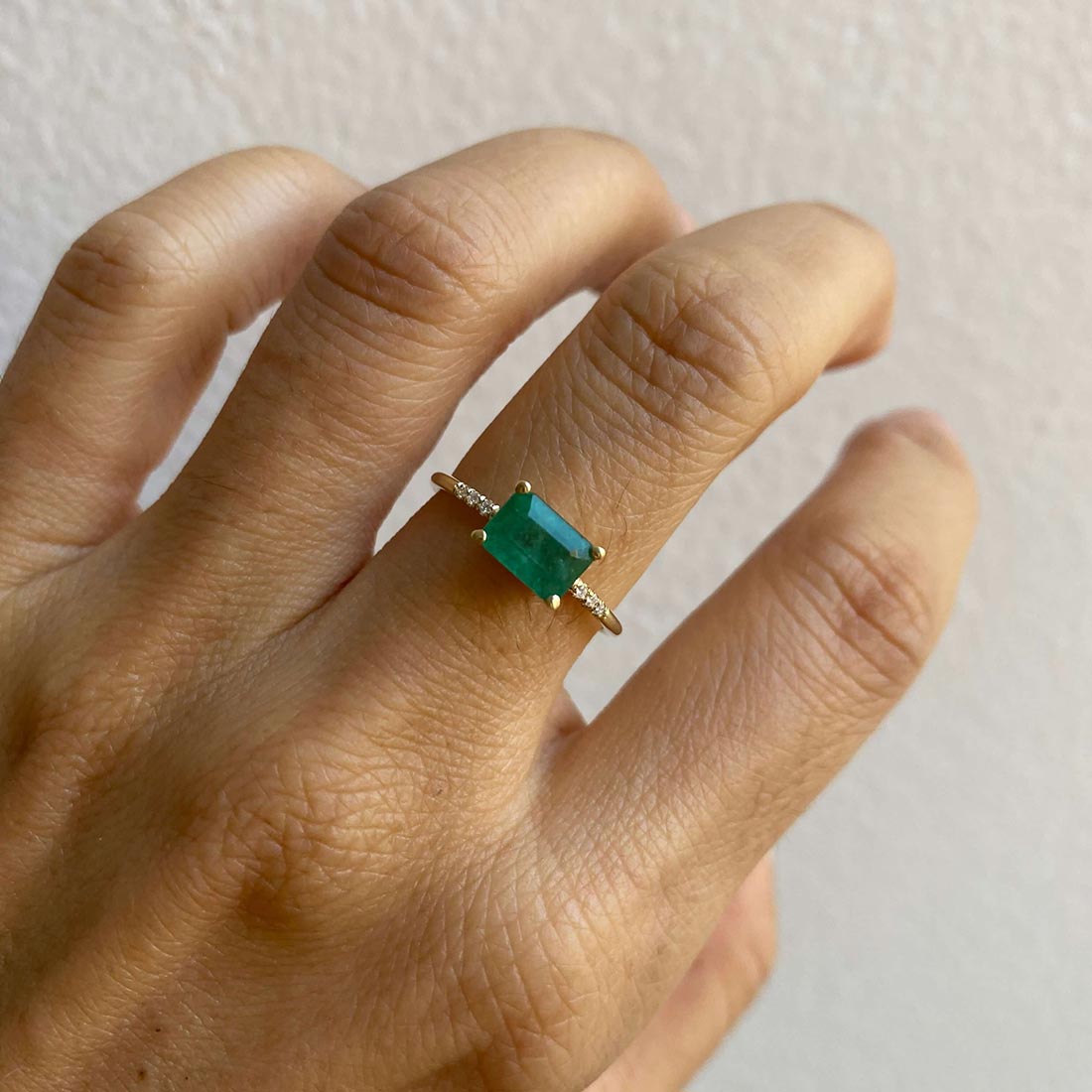 14k yellow gold custom ring with princess cut emeralds and pave white diamonds on hand