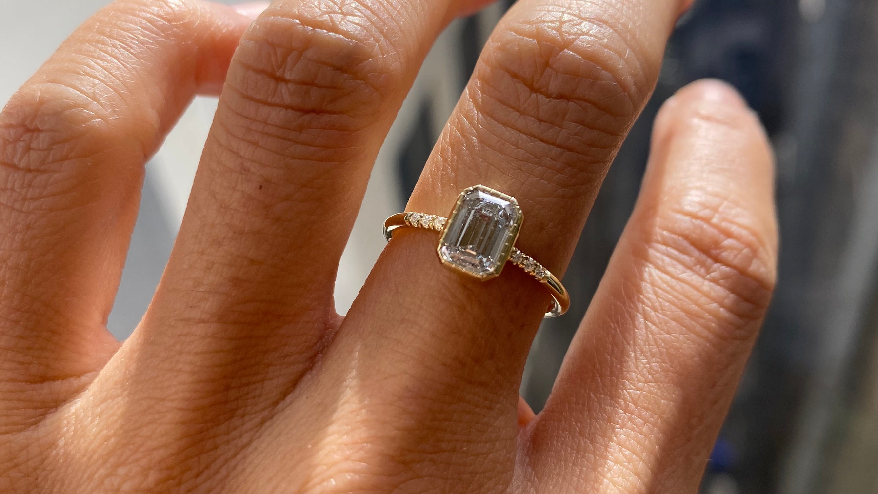 14k yellow gold custom engagement ring with princess cut white diamond center stones and white diamond pave equilibrium style stones on hand