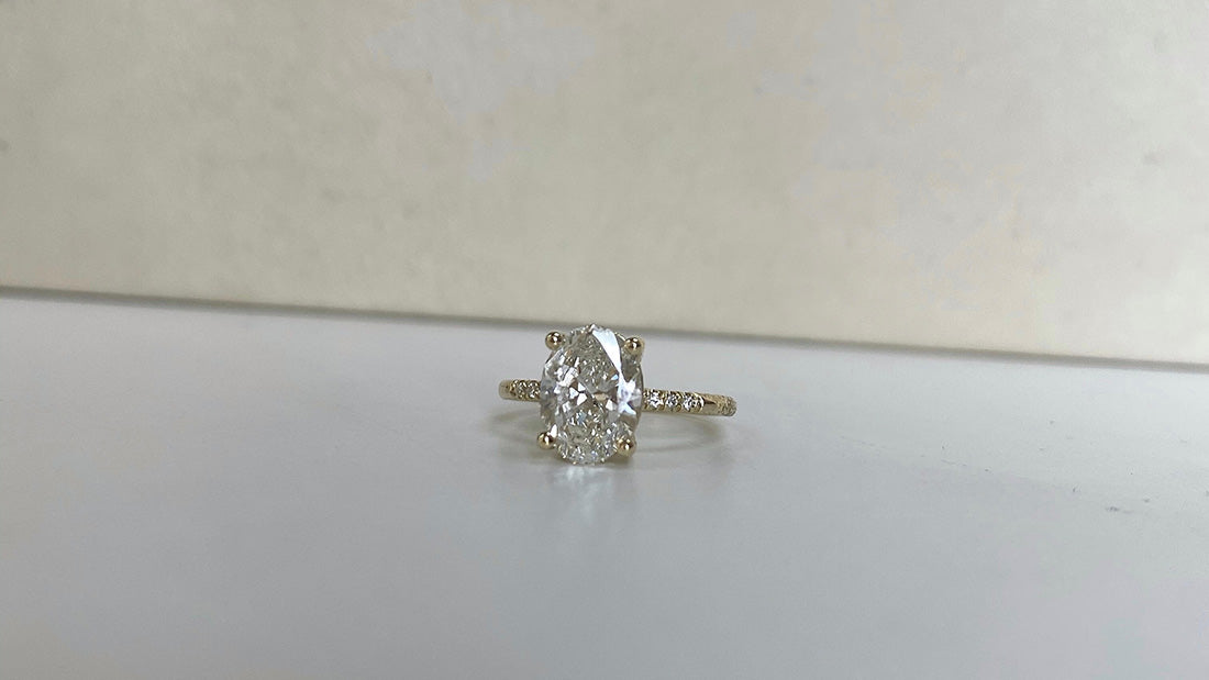14k yellow gold engagement ring with oval cut white diamond center stone and pave diamonds