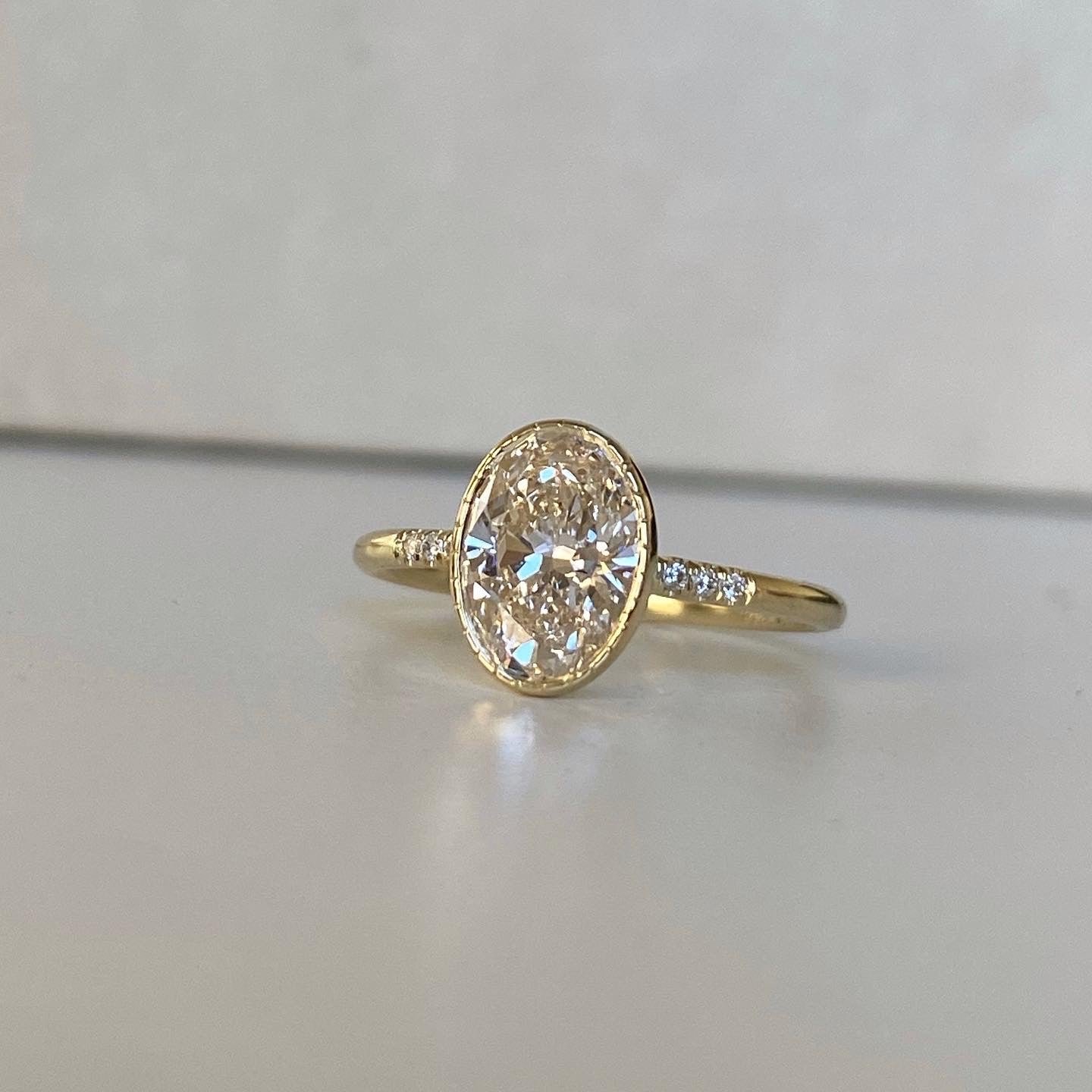 14k yellow gold custom engagement ring with oval cut white diamond center stone with pave white diamond equilibrium style stones
