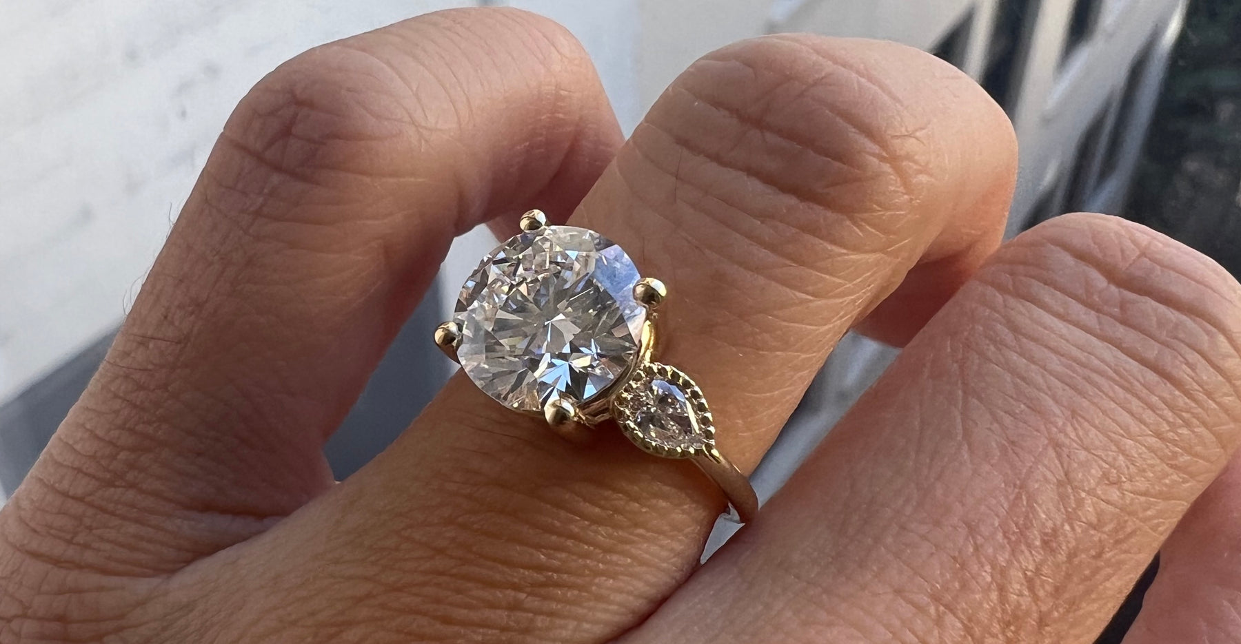 14k yellow gold custom engagement ring with round white diamond center stone and pear diamonds