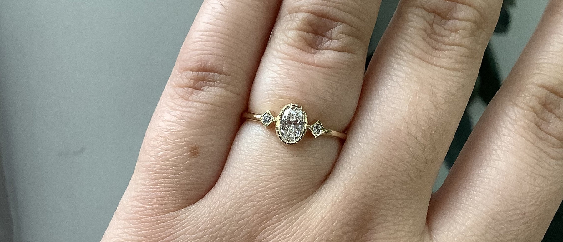 14k yellow gold custom engagement ring with oval white diamond center stone and deco diamond squares