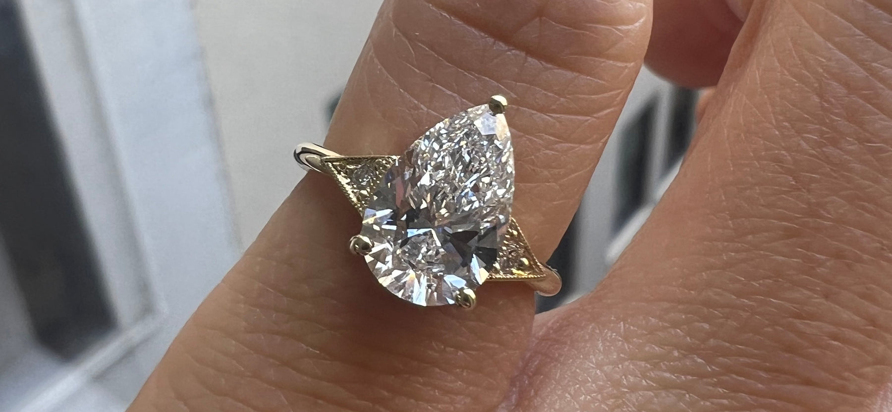 14k yellow gold custom engagement ring with pear white diamond center stone and deco diamond triangles