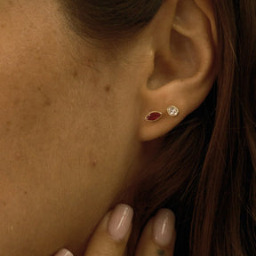 Close-up of an ear wearing two earrings with a hand touching the side of the face.