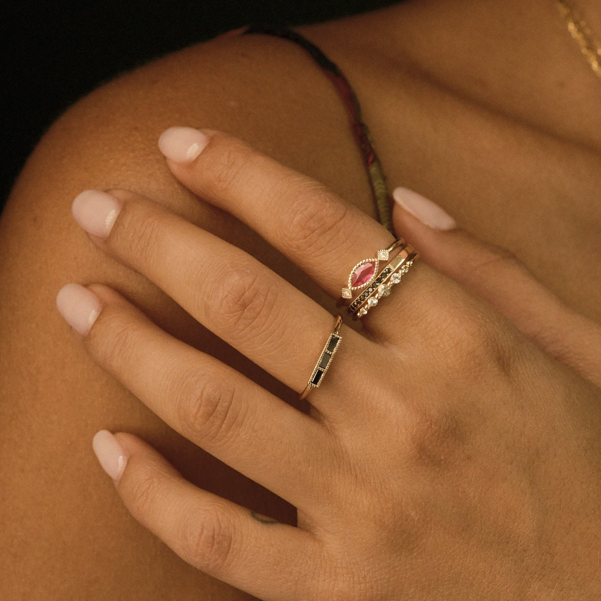 Close-up of a hand wearing two rings with a dark background
