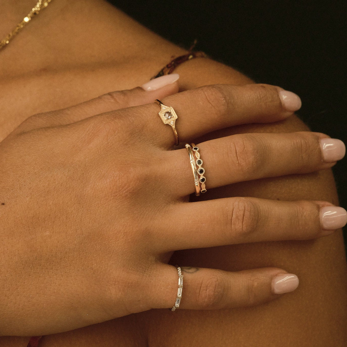 Hand wearing gold rings on a dark background