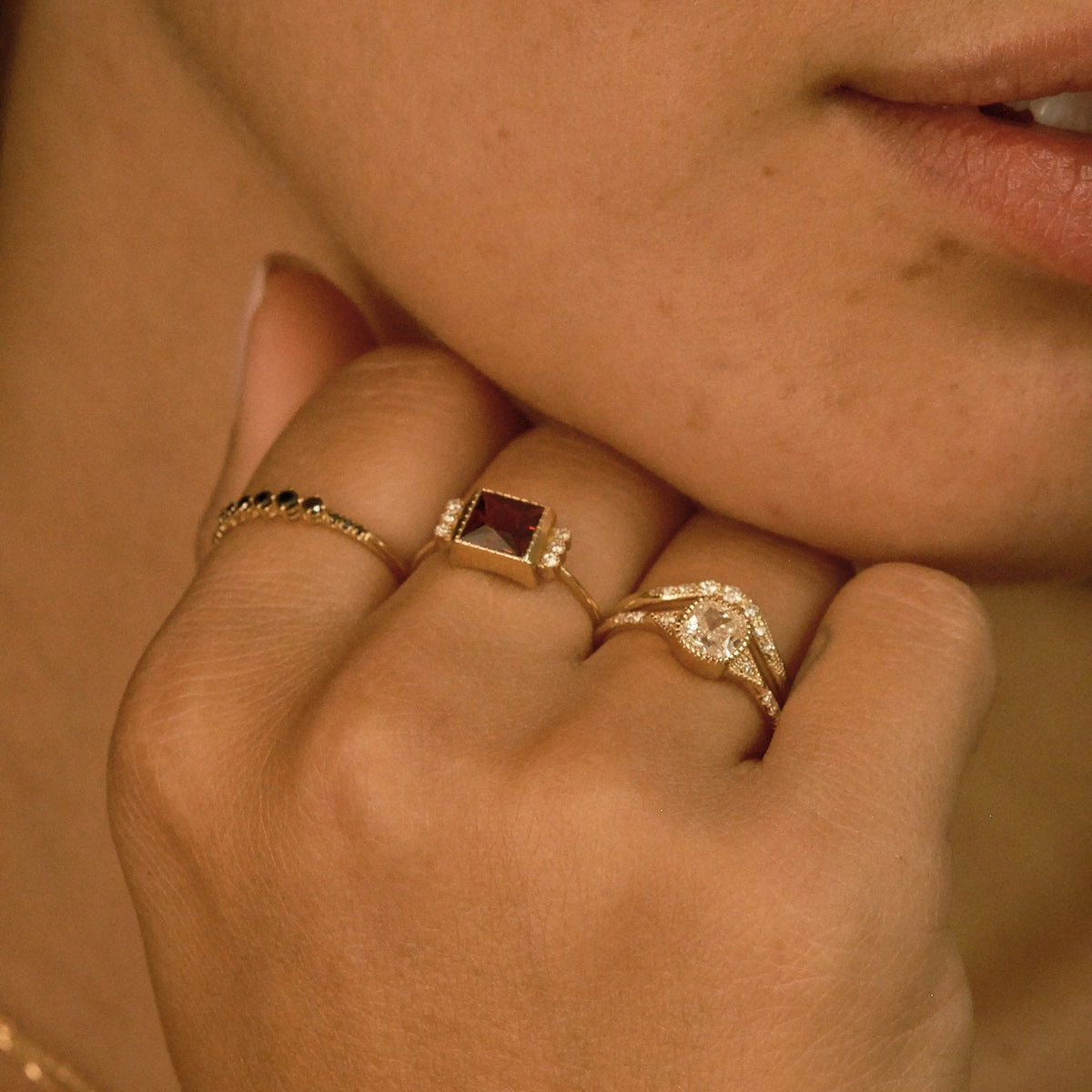 Close-up of a person's hand wearing two gold rings with gemstones.