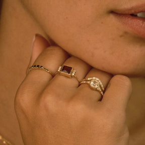 Close-up of a person's hand wearing two gold rings with gemstones.