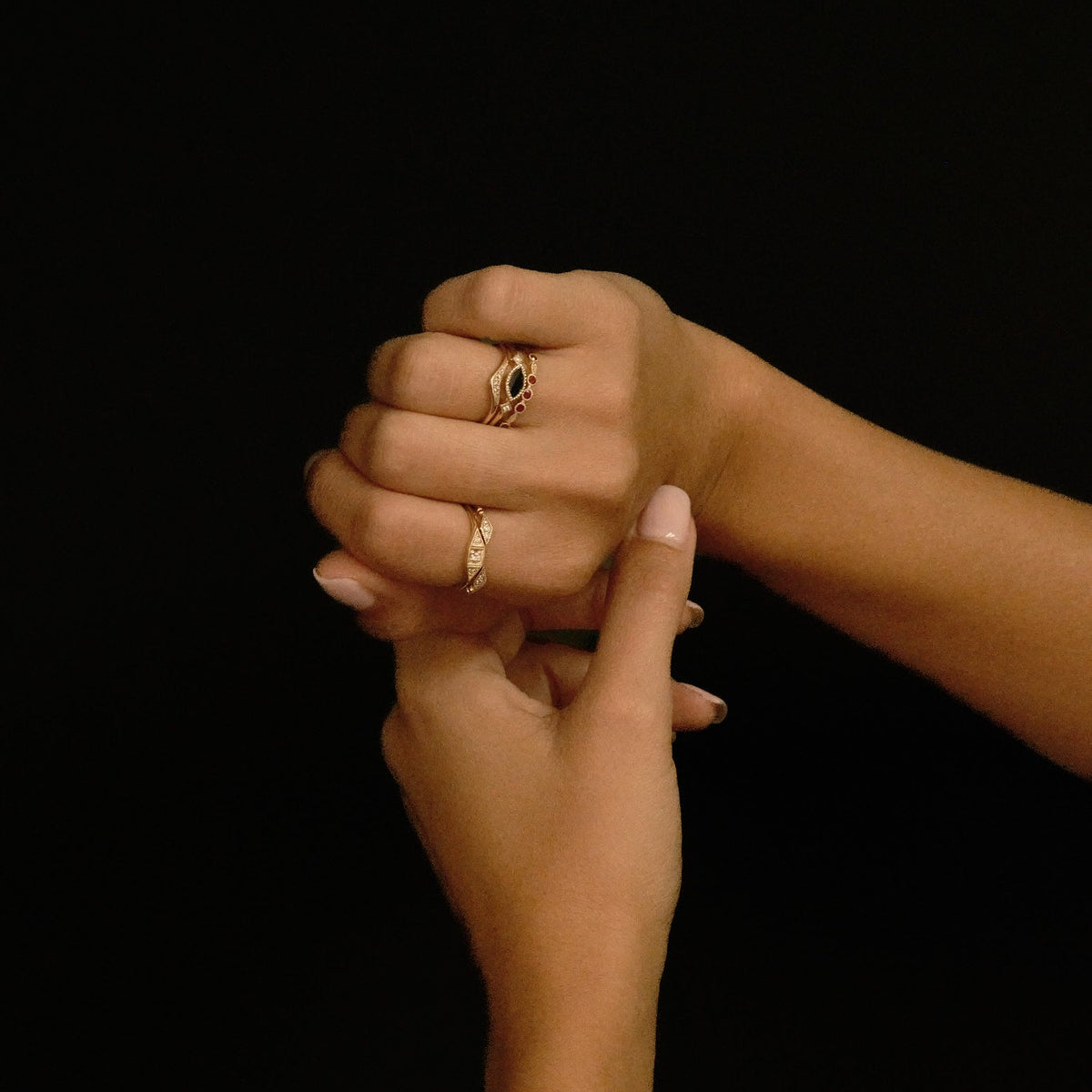 Two hands holding each other against a black background