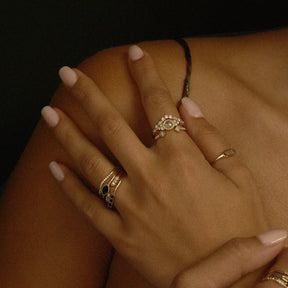 Close-up of a hand with multiple gold rings on a dark background