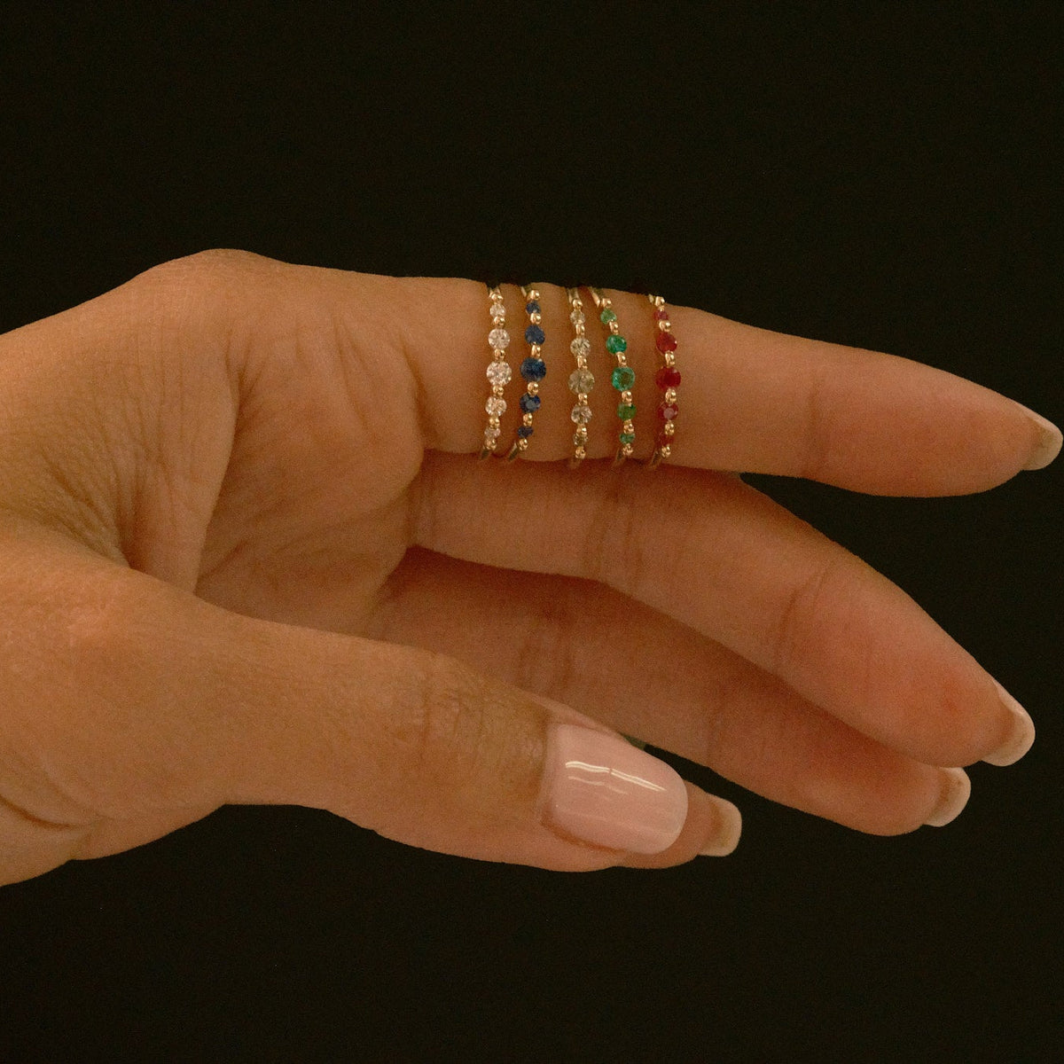 Hand wearing colorful gemstone rings