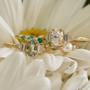 Gold ring with green gemstones on a white flower background
