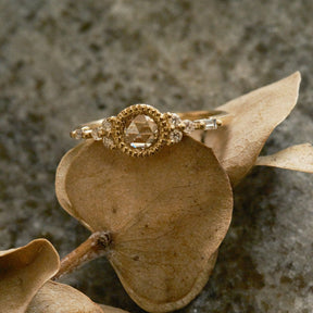 Gold ring with a diamond on a brown leaf against a textured stone background