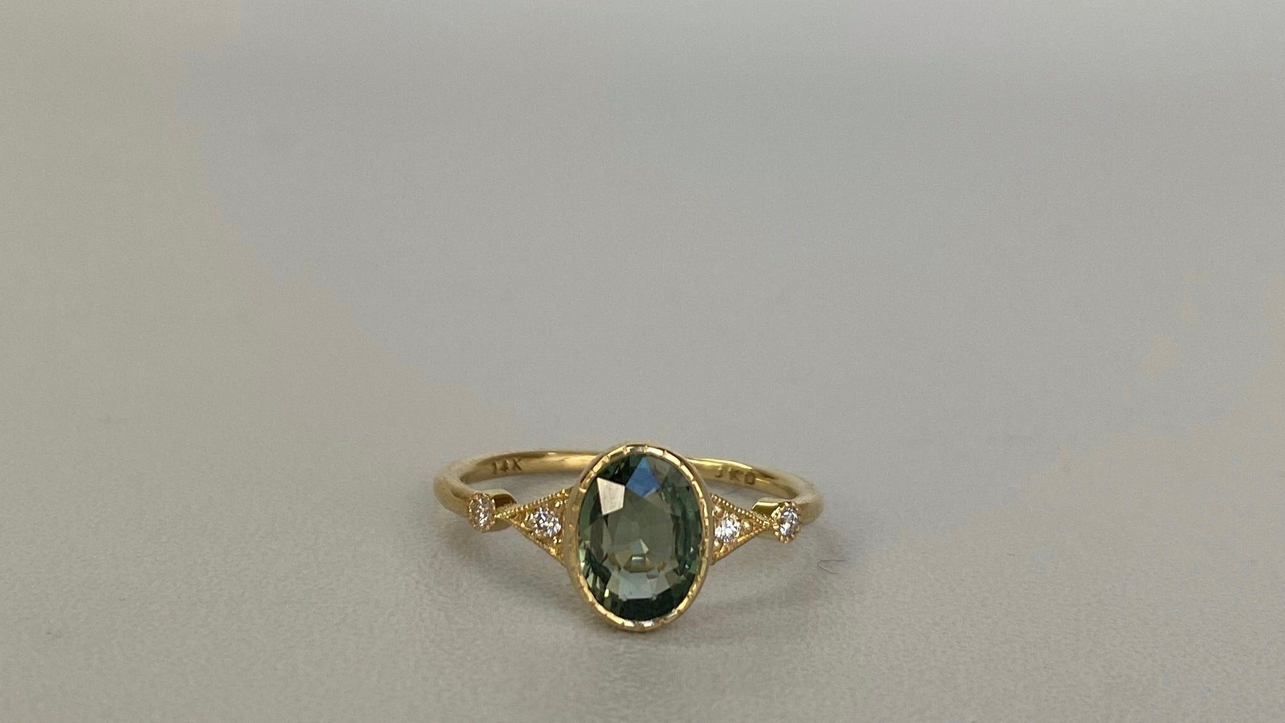 14k yellow gold custom ring with blue sapphire oval cut center stone with white diamond side stones 