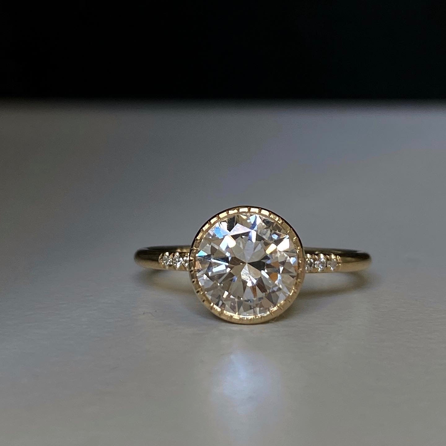 14k yellow gold custom engagement ring with white diamond round cut center stone and milgrain detail and pave white diamonds