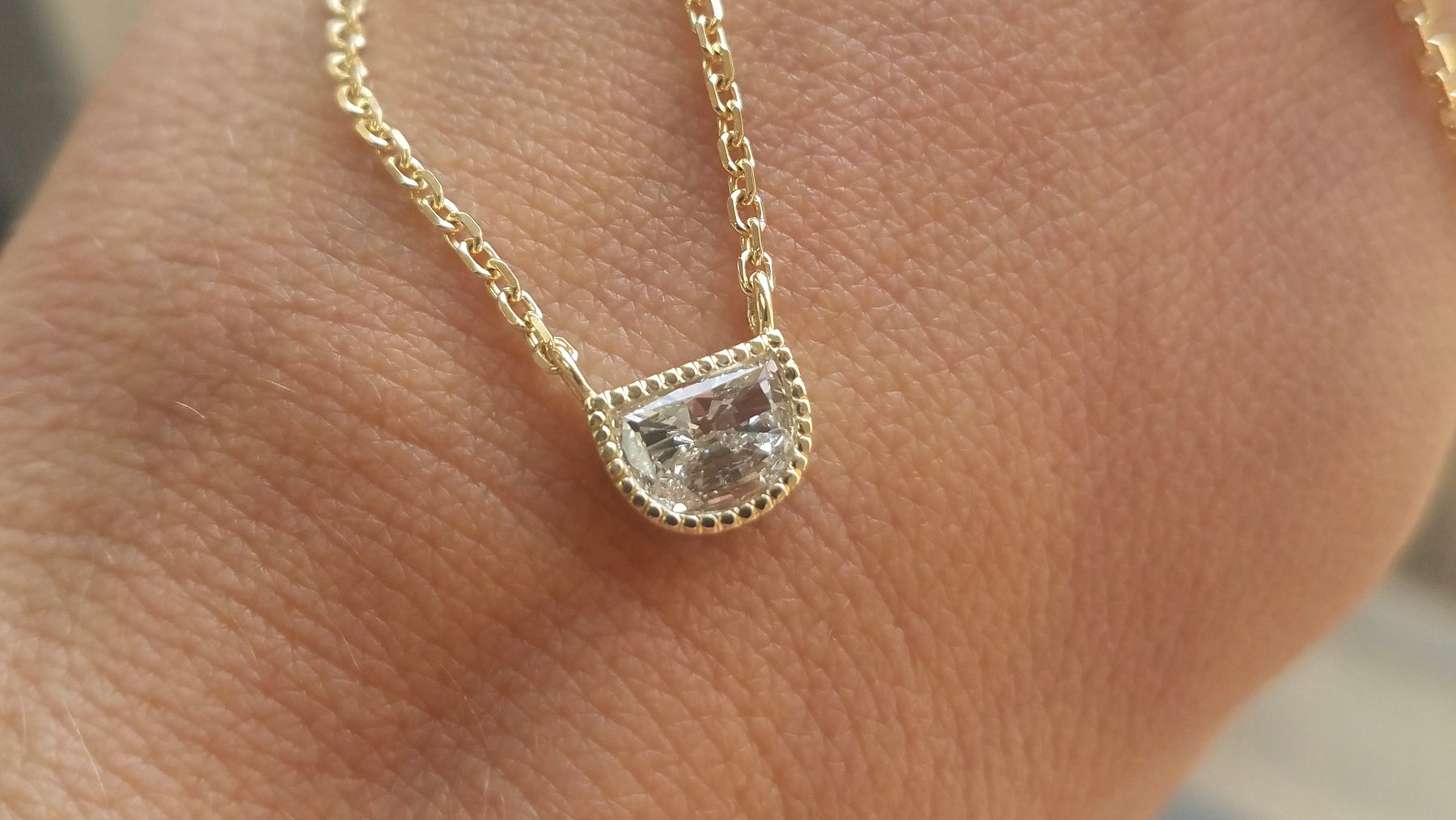 14k yellow gold custom necklace with white diamond center stone with milgrain detail 