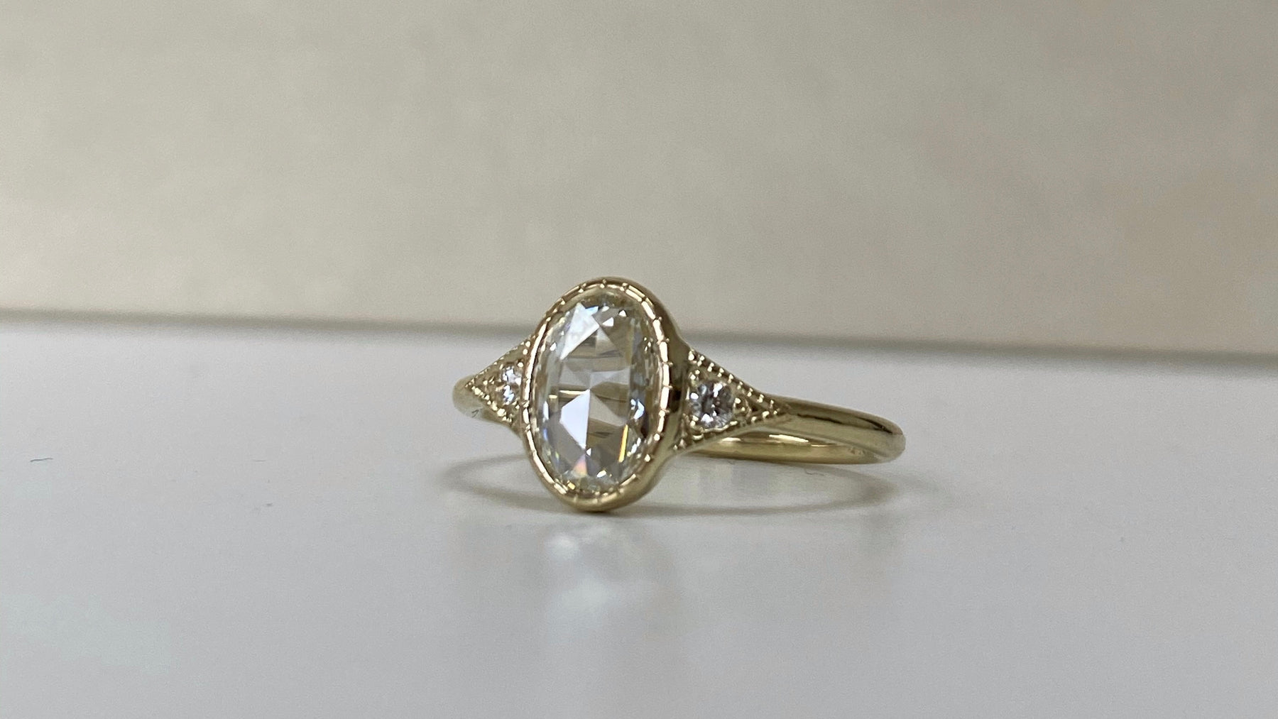 14k yellow gold custom engagement ring with oval cut white diamond milgrain detail and white diamond side diamonds