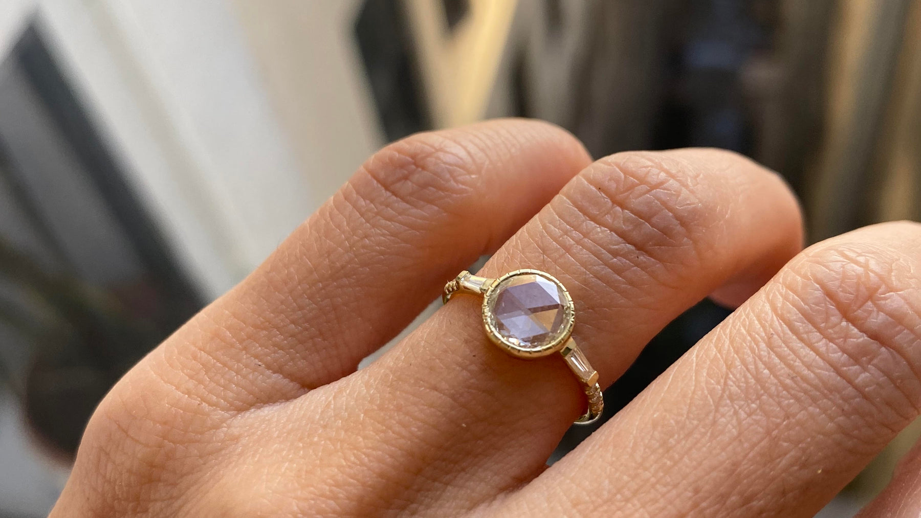 14k yellow gold custom engagement ring with round white diamond center stone with baguette side white diamonds on hand